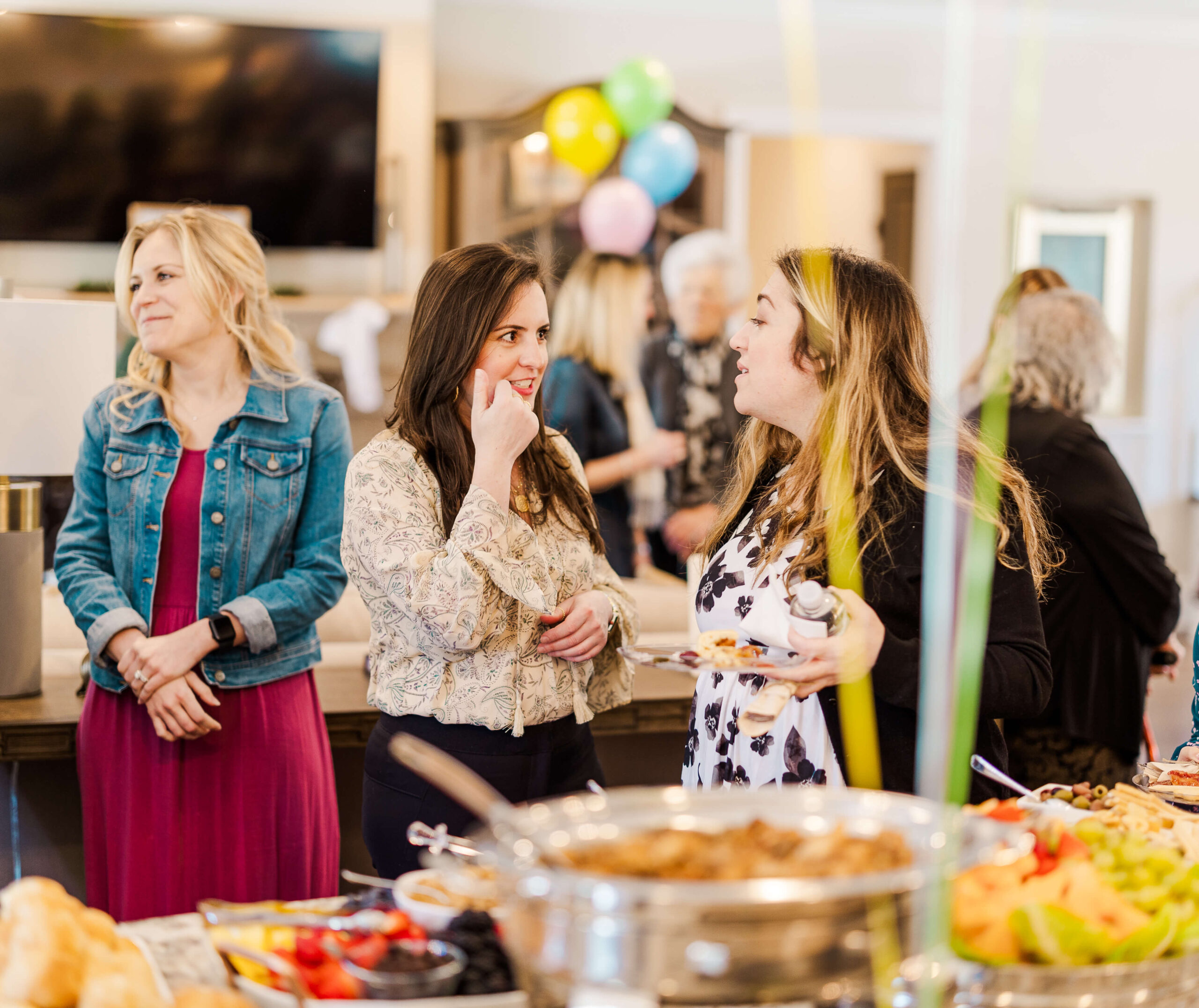 A group of woman gather around a buffet table with various dishes during a celebration catered by bakeries in Fayetteville, NC