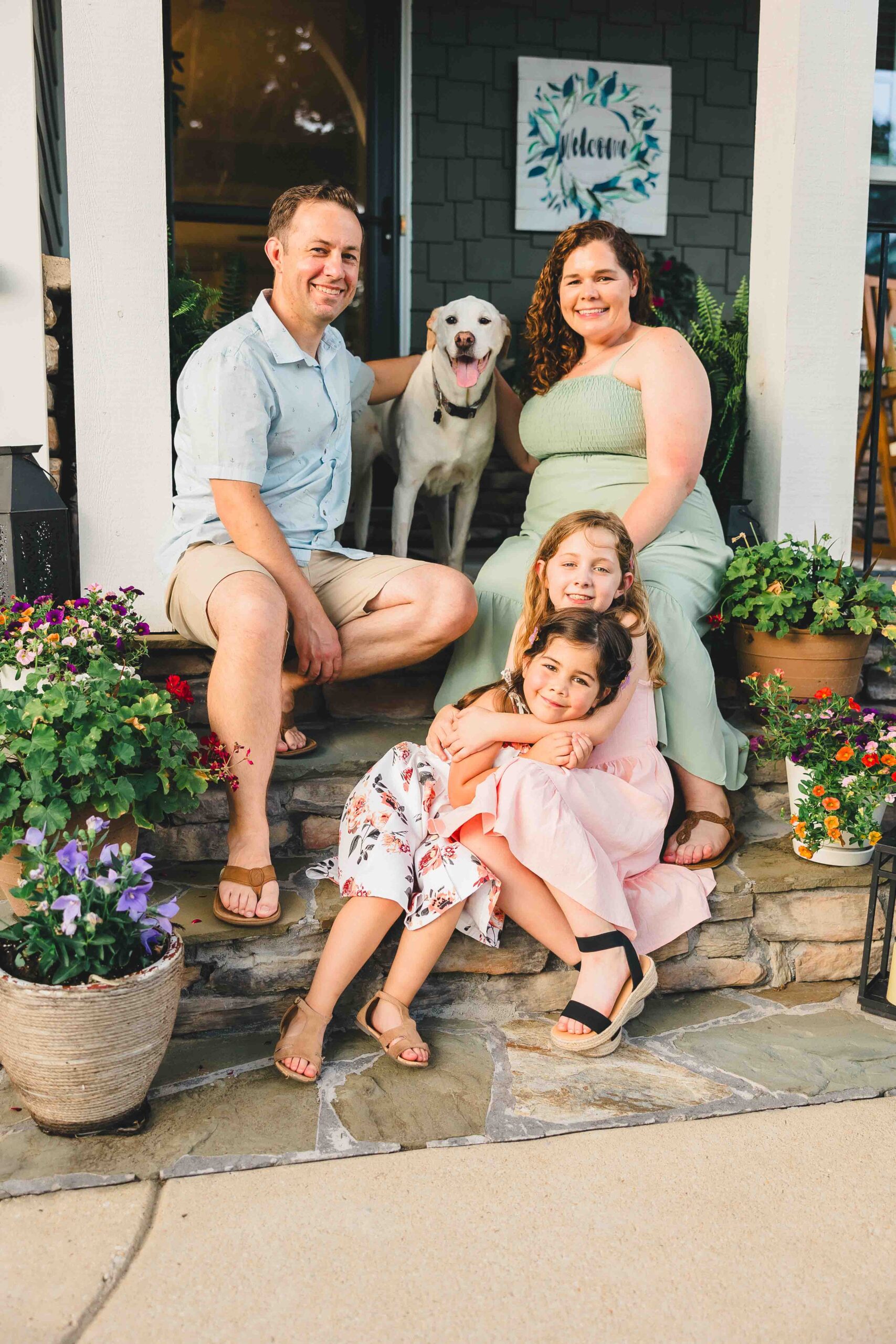 A family of four sits on the steps of a porch hugging each other and a dog after visiting pediatricians in Fayetteville