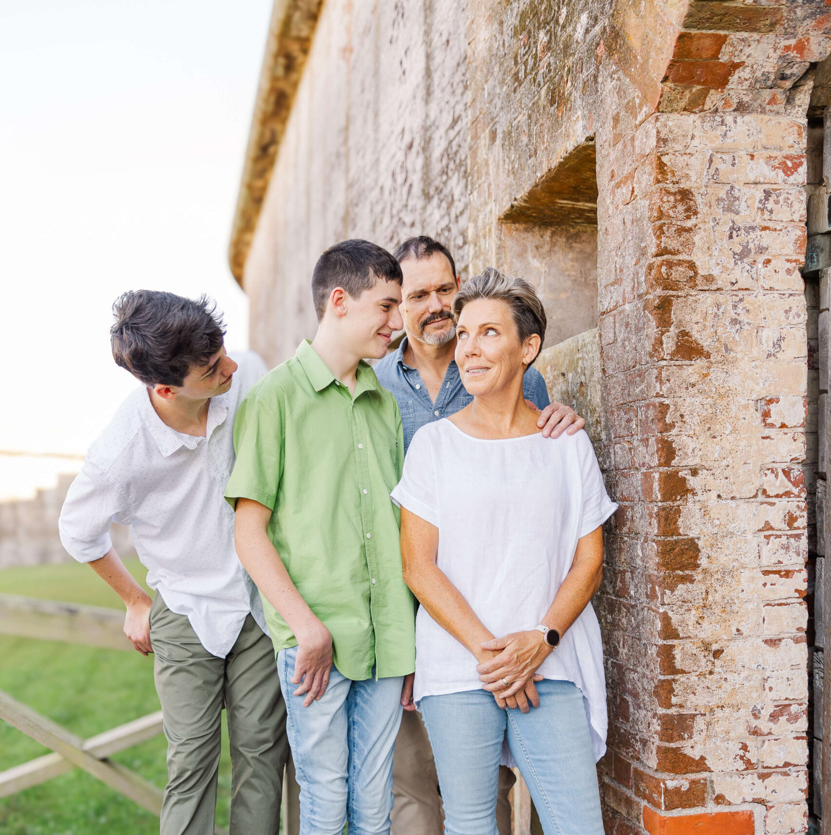 A family of four stands on a wooden walkway by a stone wall smiling at mom after visiting bowling alleys in Fayetteville nc