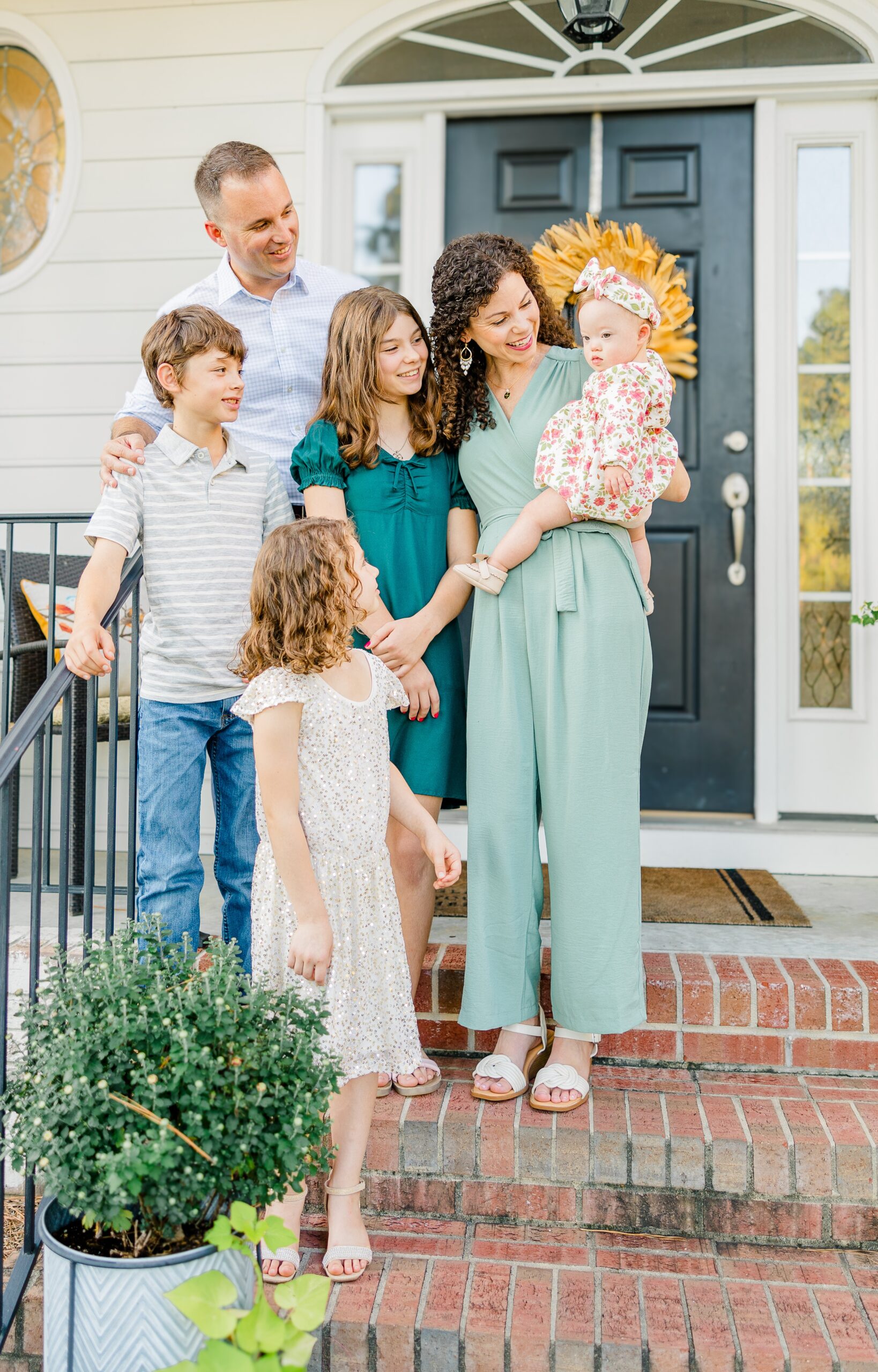 A family of six stands on a porch all smiling at the baby in mom's arms before visiting daycares in fayetteville nc