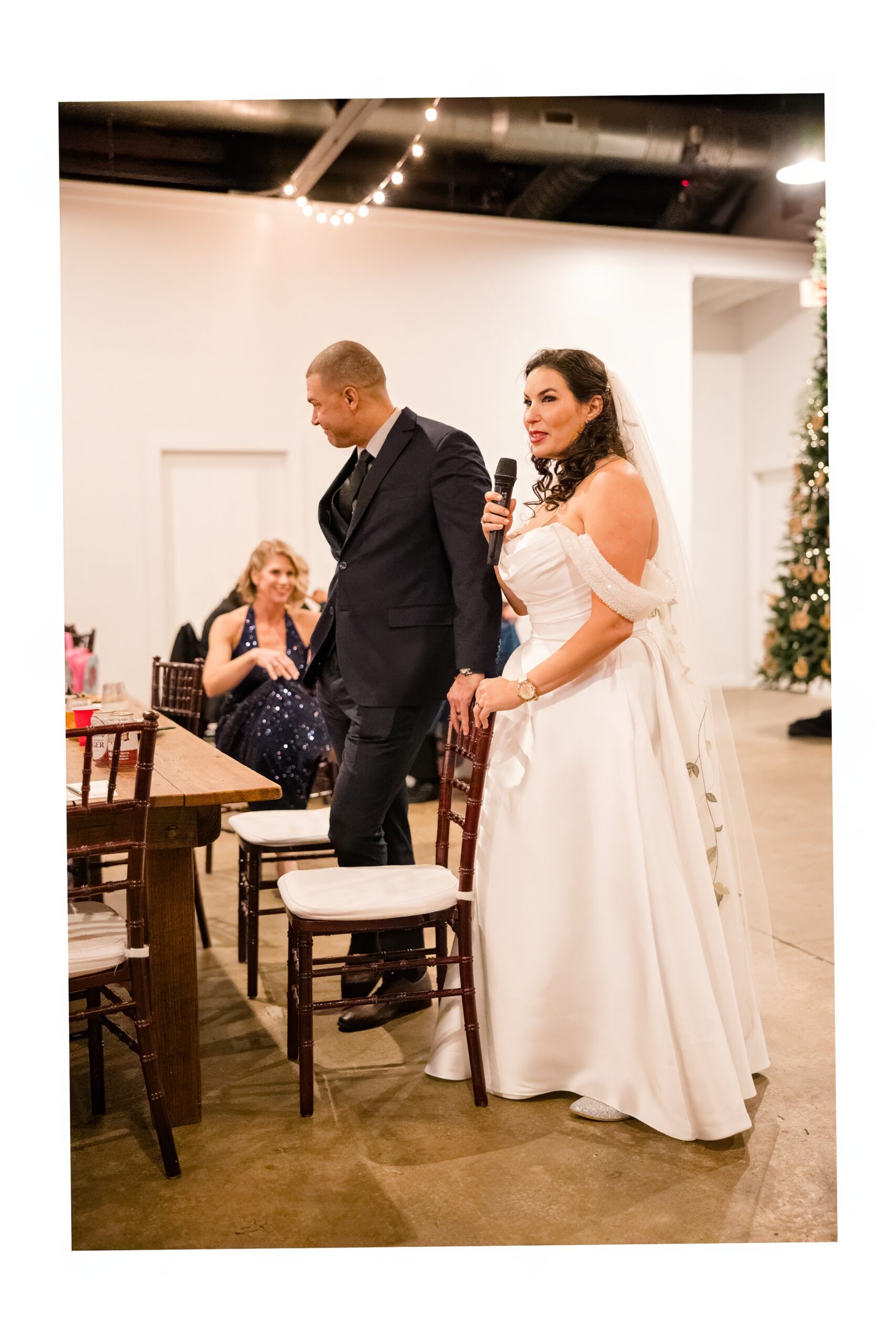 A bride gives a toast while standing next to her groom during their reception with a microphone from djs in fayetteville nc.