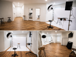 A photography studio ideal for corporate headshots in Fayetteville, NC, featuring a white backdrop, professional lighting, stools, and hardwood floors. The bright space has white walls with doors and windows visible in the background.